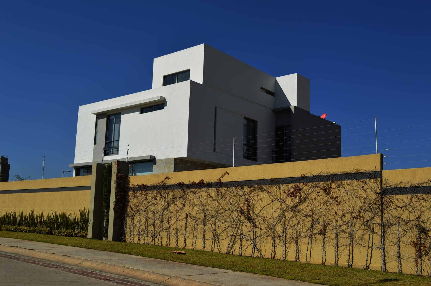 Cerca eléctrica sobre la barda perimetral de una casa moderna de dos niveles