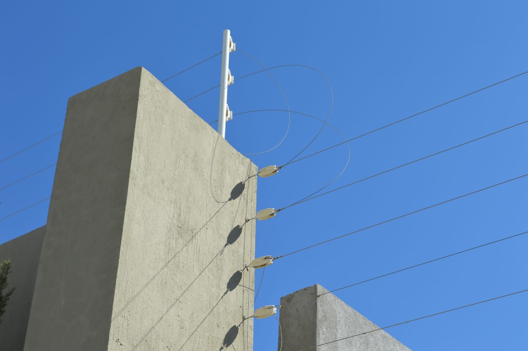 Remate de esquina de una cerca eléctrica con sus hilos tensados contra el cielo