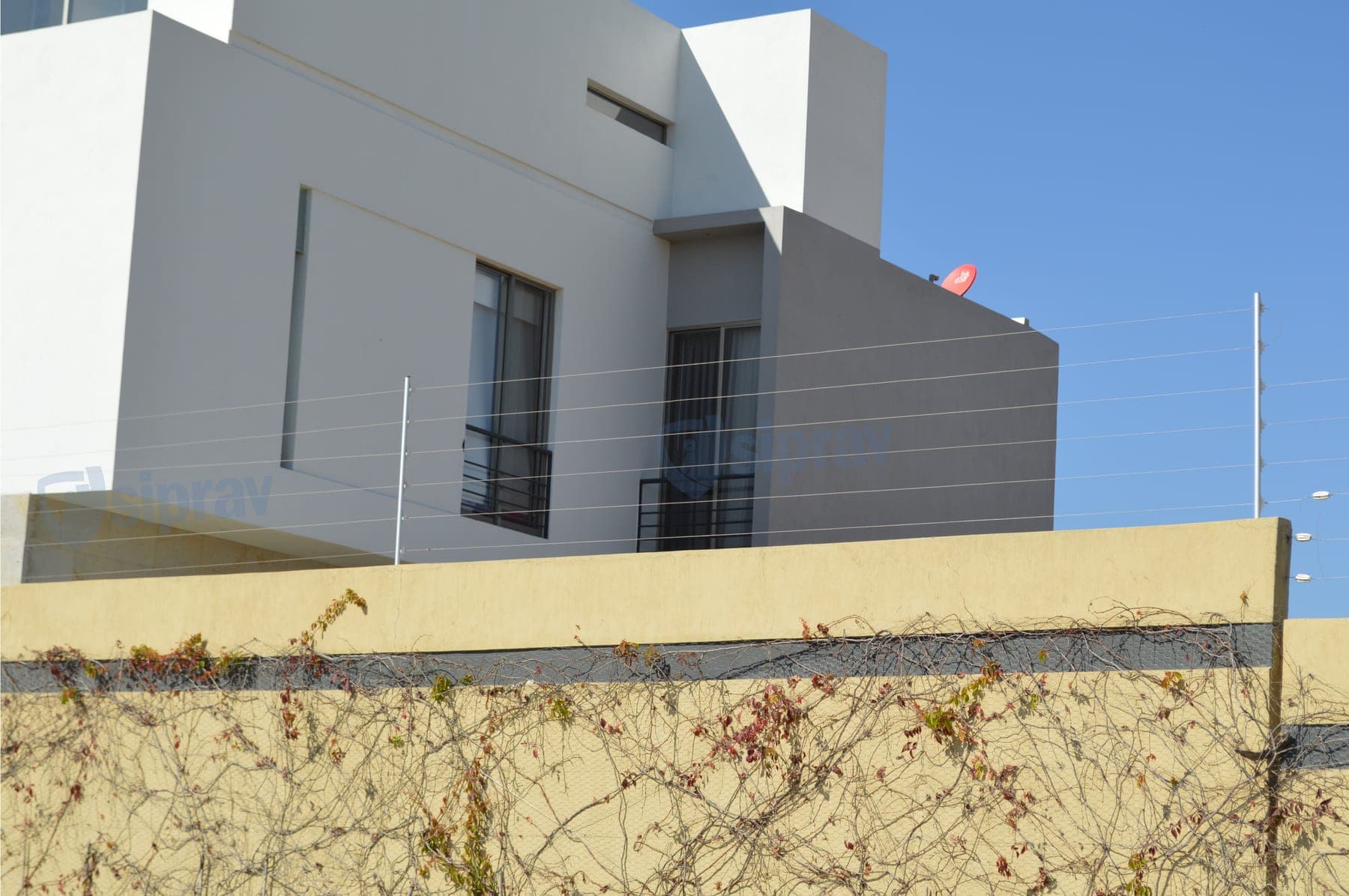 Cerca eléctrica en la barda lateral de una residencia moderna de líneas rectas