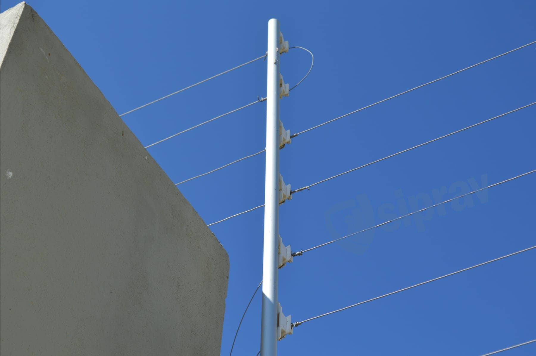 Detalle de un poste de cerca eléctrica con cinco aisladores contra el cielo