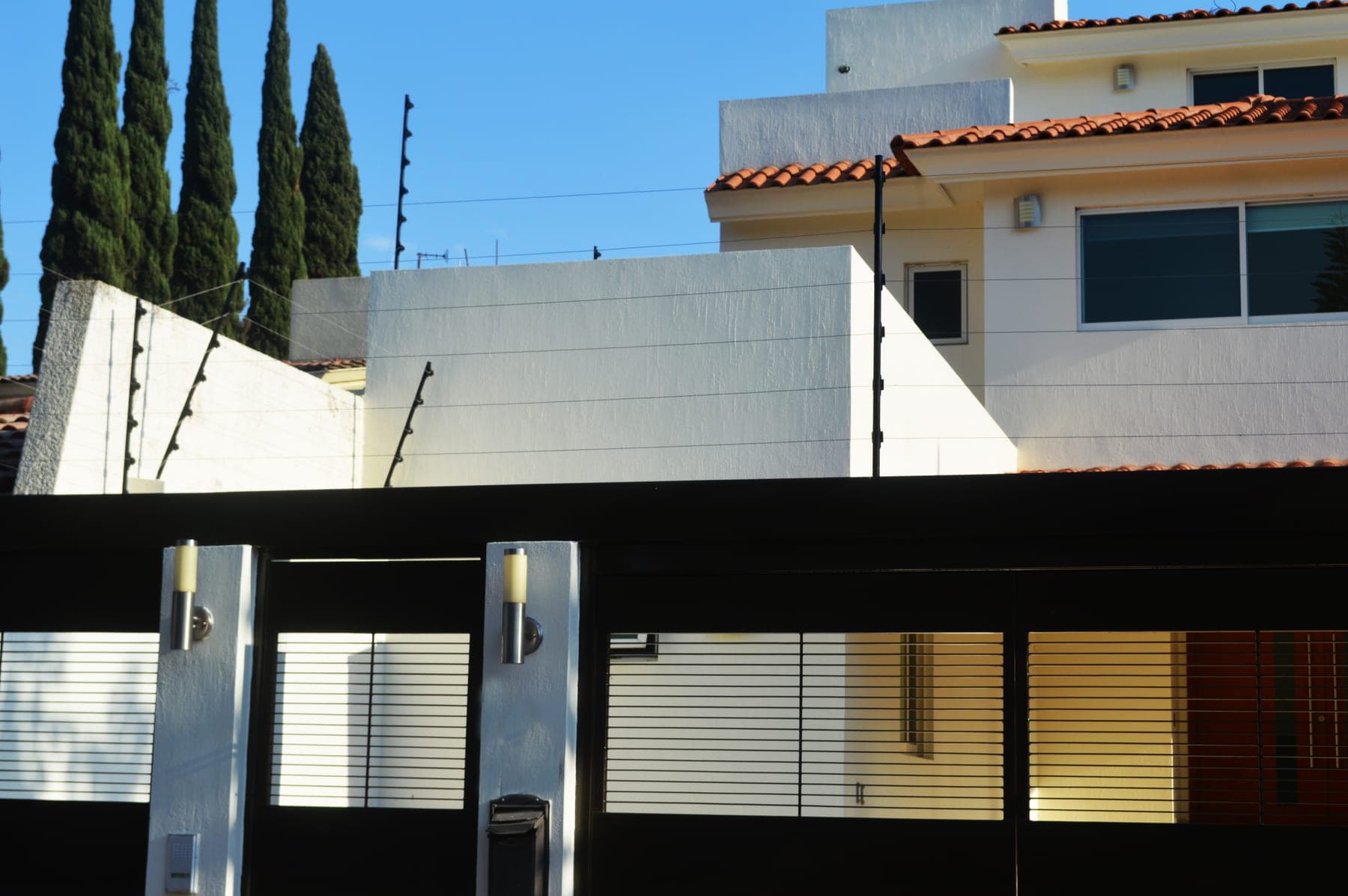 Cerca eléctrica sobre el portón de acceso de una casa, con el número visible