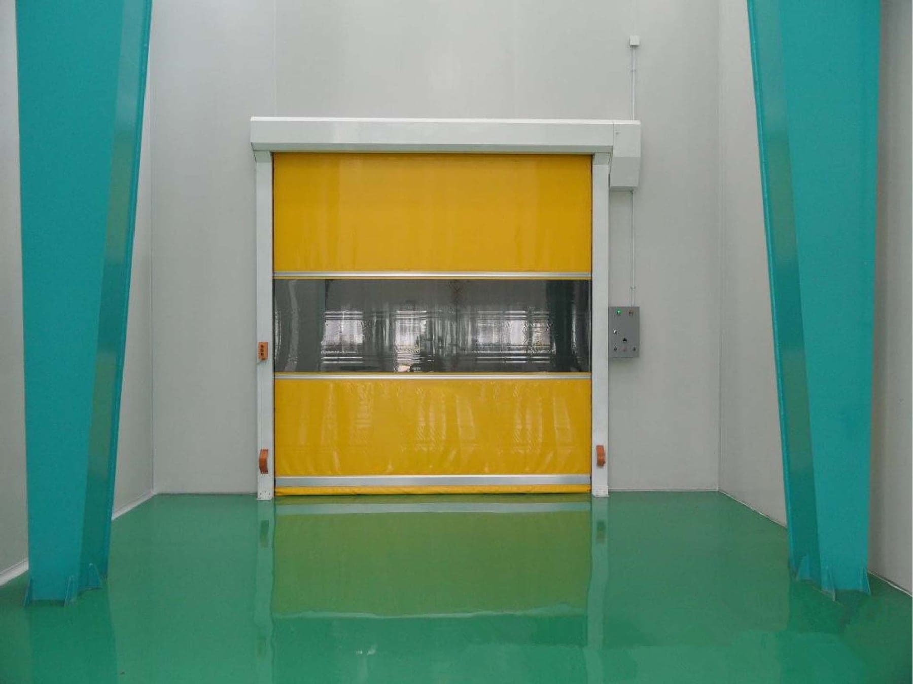 Puerta rápida amarilla cerrada en una sala de proceso de piso epóxico verde