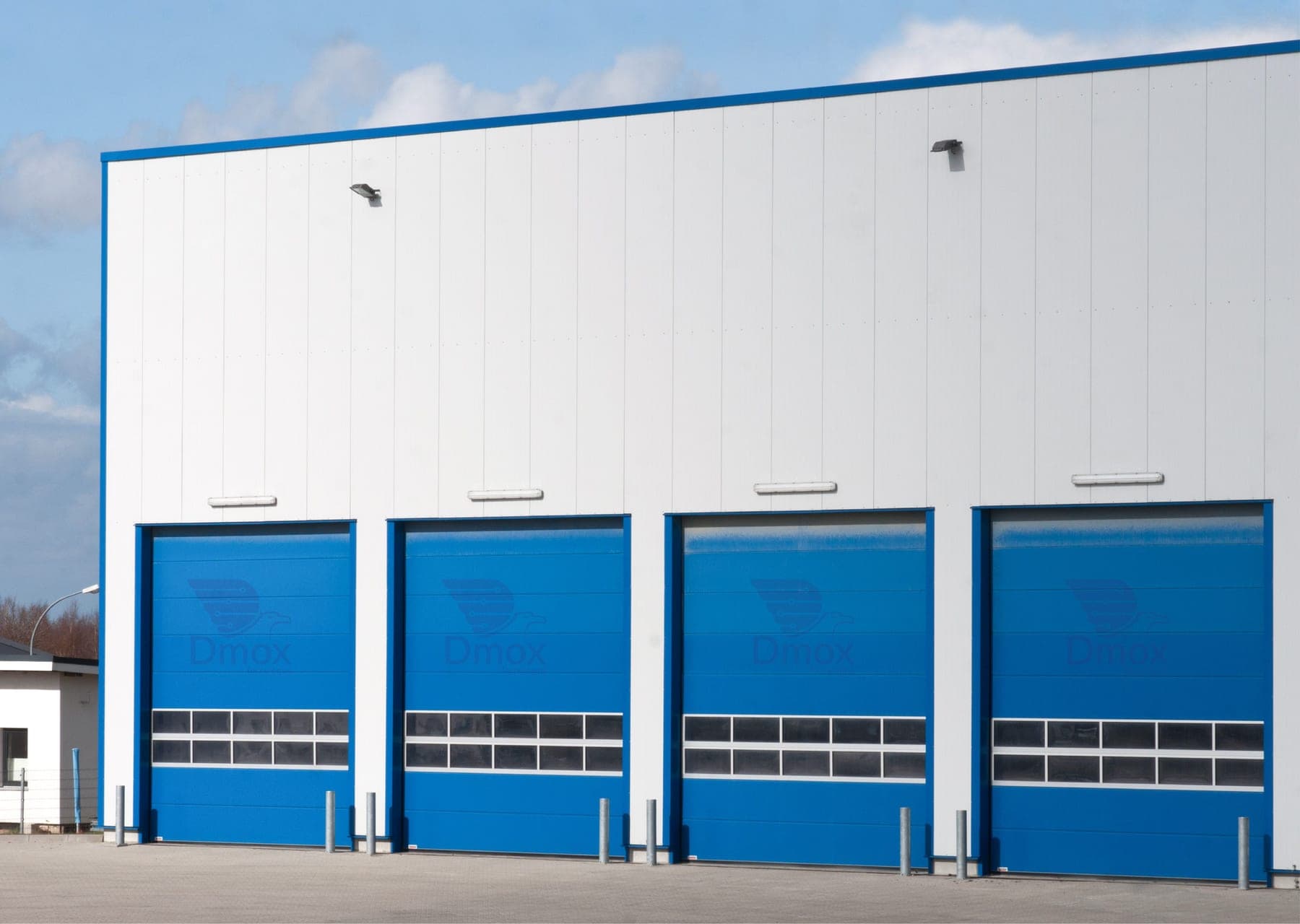 Fachada industrial con cuatro puertas rápidas azules alineadas sobre los andenes