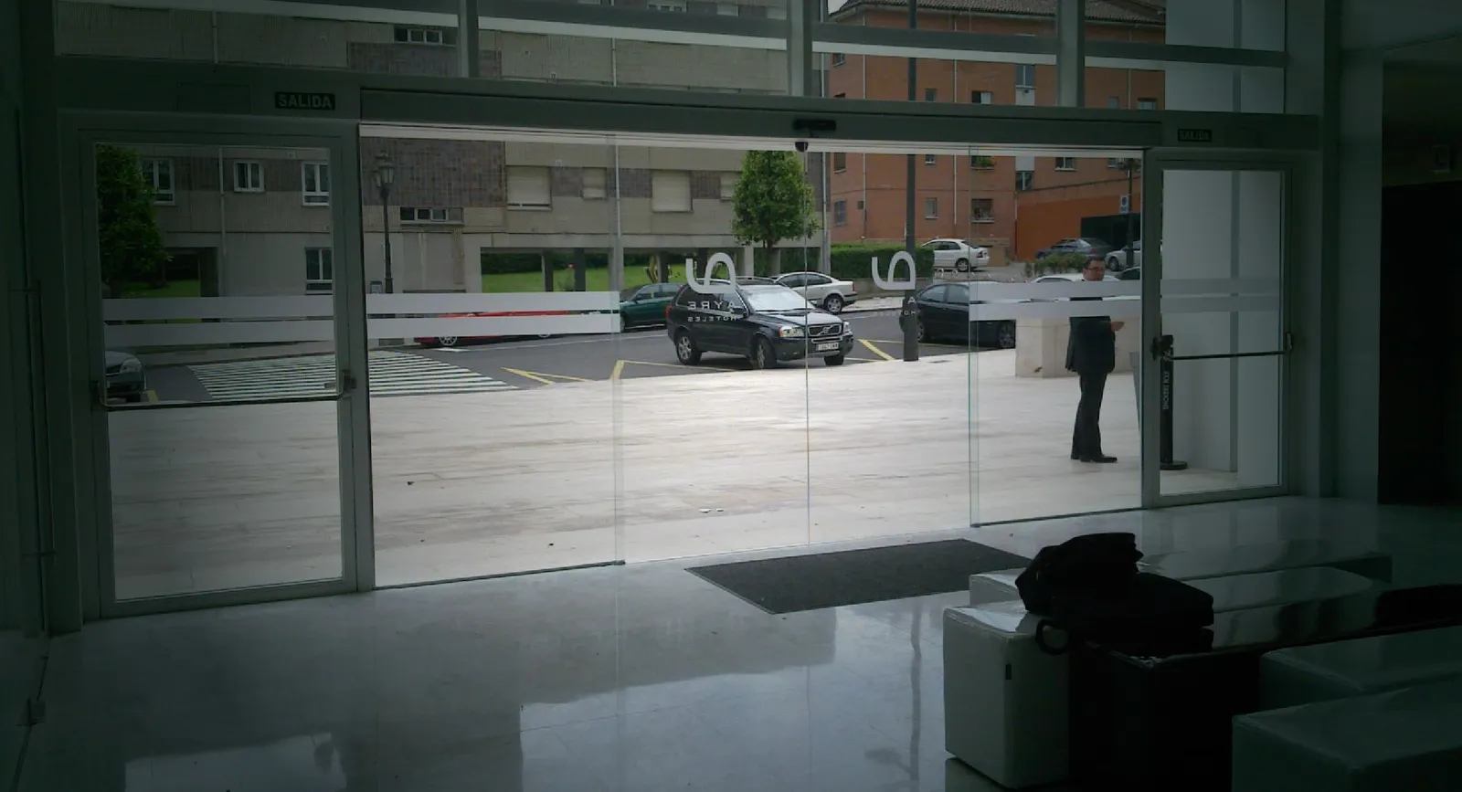 Puerta automática todo cristal (All Glass) en el acceso a un edificio de oficinas vista desde el lobby interior