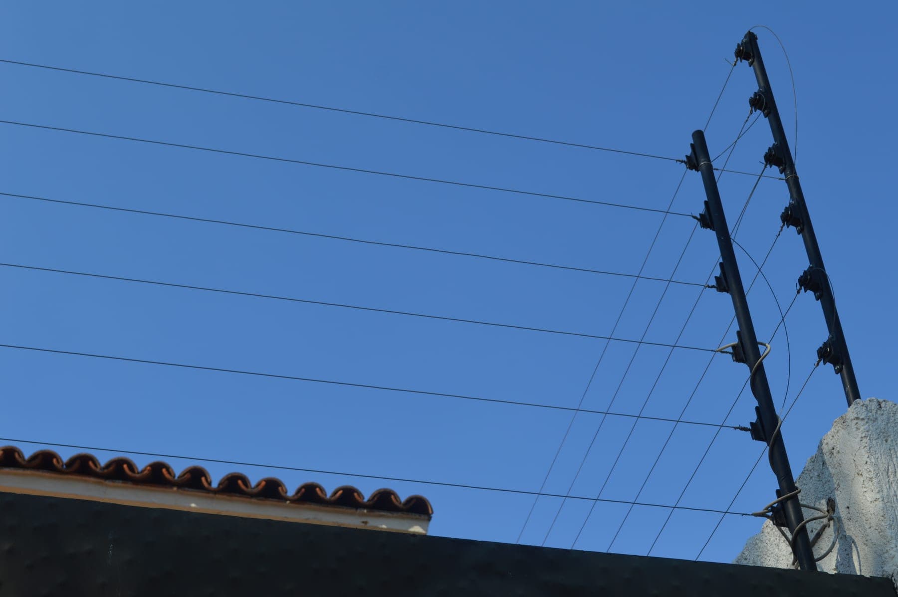 Poste de esquina de una cerca eléctrica con sus hilos electrificados conectados al energizador